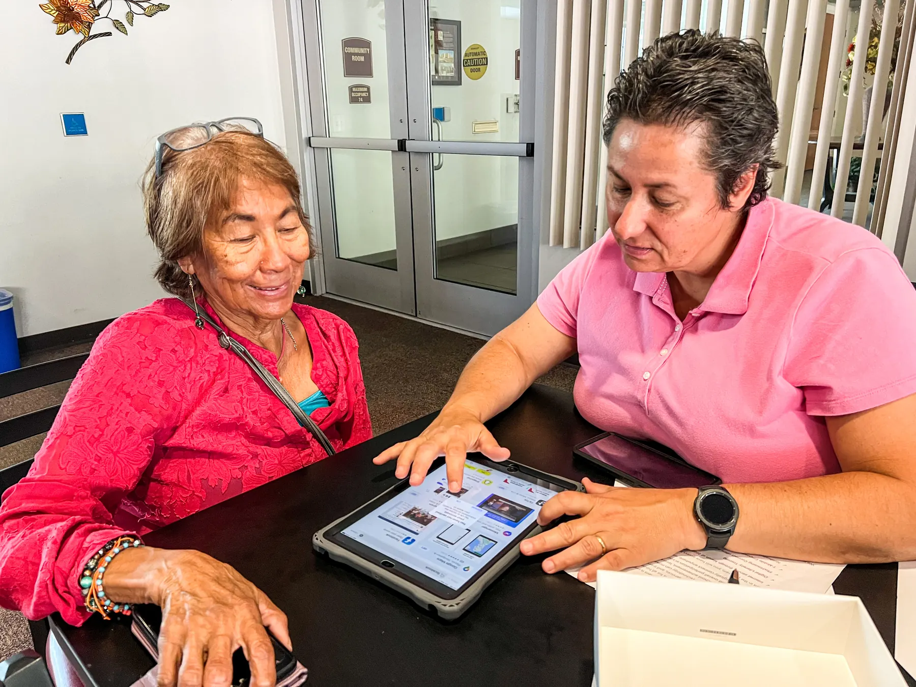 A community helper shows an older resident how to use a health app